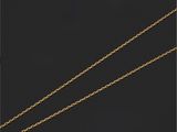 a close up of a gold necklace with a diamond on a black background