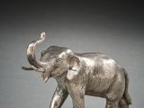 silver elephant figurine on a gray surface with a black background