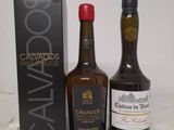 two bottles of cavados and a box of wine on a table