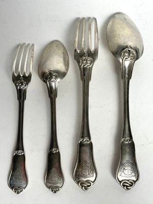four forks and spoons are lined up on a white surface