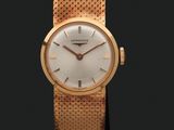 gros plan d'une montre-bracelet en or sur une surface noire