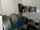 several pans and pans are stacked on a metal shelf in a kitchen