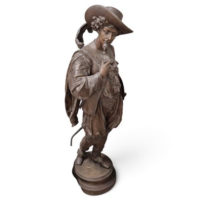 une statue en bronze représentant un homme avec un chapeau et une canne