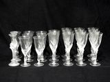 six clear wine glasses are lined up on a black background
