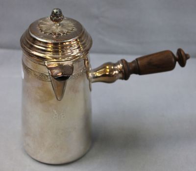 an antique silver coffee pot with a wooden handle on a table
