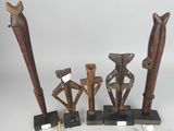 three wooden sculptures of people are on display on a white surface