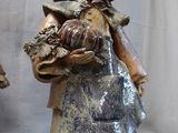 three figurines of a woman with a hat and a bag