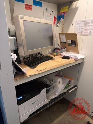 un ordinateur et une imprimante posés sur un bureau dans une petite pièce