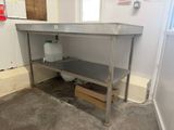 a stainless steel work table in the corner of a room