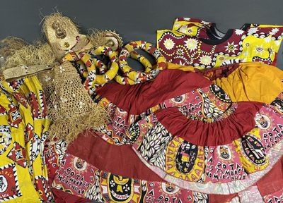 une poupée assise sur une robe colorée