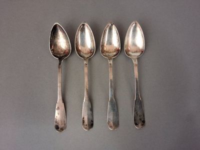 quatre cuillères sont alignées en rang sur une table