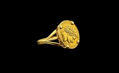 Gros plan sur une bague en or ornée d'une pièce de monnaie
