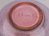 a pink vase with a brown rim on a white table