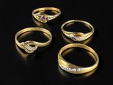 three gold rings with diamonds on a black surface