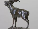 bronze sculpture of a stag standing on a rock on a white surface