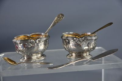 deux bols en argent avec des cuillères, posés sur une table