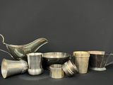 several silver cups and saucers on a table with a black background