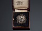 an image of a small silver medal in a box on a black background