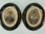 two framed portraits of a man and a woman in black and gold
