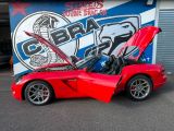 a red sports car with its hood open in front of a garage