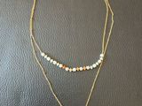 a gold necklace with a coin and a beaded chain
