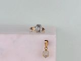 a gold ring with a white diamond on top of a pink marble block