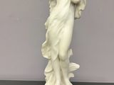statue d'une femme tenant une pomme rouge posée sur une table