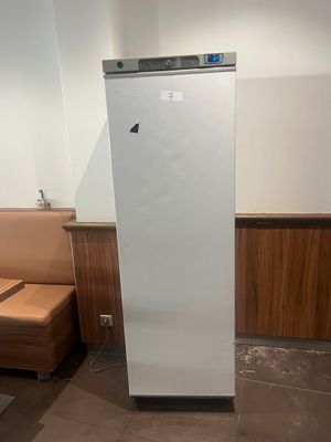 un réfrigérateur blanc dans un coin de la pièce, à côté d'un canapé