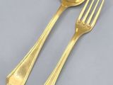 two gold spoons and a fork on a gray surface
