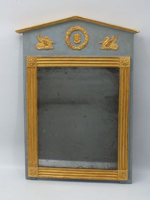 un petit miroir avec un cadre doré sur fond blanc