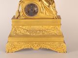 a gold clock with a statue on top of it