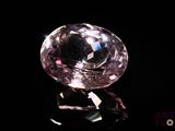 pink diamond on a black surface with a black background