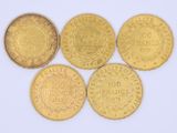 five gold coins of different sizes and shapes on a white surface