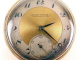 a close up of a pocket watch with a gold dial