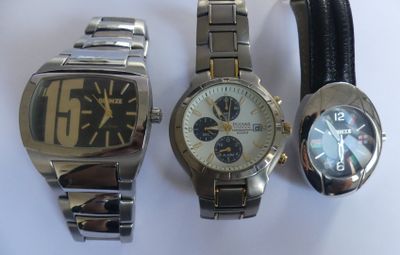 three watches are sitting next to each other on a white surface