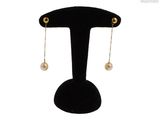 une paire de boucles d'oreilles ornées de perles suspendues à un support noir
