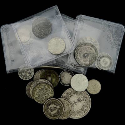 plusieurs types de pièces de monnaie dans des sachets en plastique, posés sur une surface noire