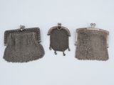 trois porte-monnaie en métal argenté posés sur une surface blanche