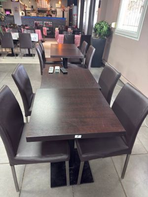 une table et des chaises dans une pièce avec beaucoup de fenêtres