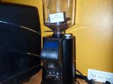 a black coffee grinder sitting on a counter next to a laptop