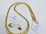 a gold necklace and earring set on a white surface