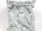 un vase blanc orné d'une statuette, posé sur une surface blanche