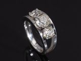 a close up of a three stone diamond ring on a black surface