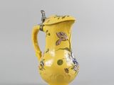 a yellow vase with a yellow lid on a gray surface