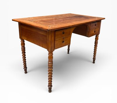 un vieux bureau en bois à deux tiroirs et aux pieds tournés