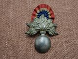 un petit objet en métal orné d'une fleur rouge, blanche et bleue
