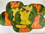 four placemats with birds and palm leaves on them on a white surface