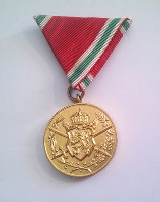 medal with red, white, and green ribbon on white surface