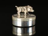 a silver figurine of a dog on top of a coin