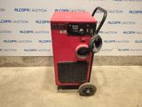 a red machine sitting on top of a cement floor next to a wall
